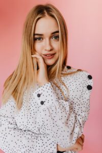 Green-eyed lady in white blouse looking to camera with interest. Studio shot of sensual caucasian m